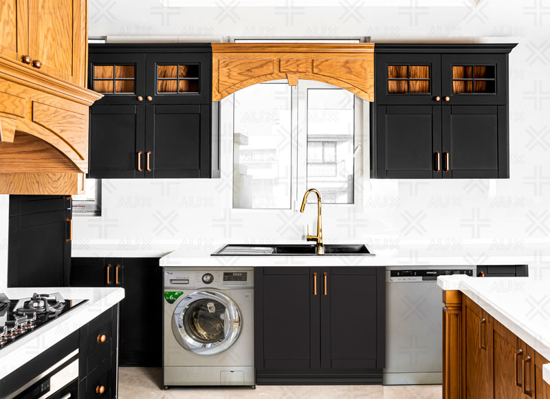 کابینت مشکی و چوبی با صفحه سفید، سینک زیر پنجره و جزئیات طلایی در آشپزخانه‌ای شیک و کاربردی.
