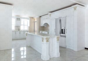 نمای کامل از آشپزخانه کلاسیک با کف براق، کابینت سفید و نورگیر قوسی