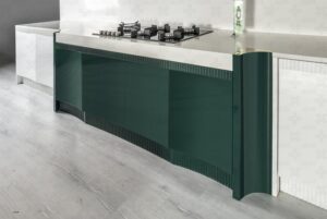 نمای نزدیک کابینت زمینی با طراحی منحنی و رنگ سبز تیره، همراه با صفحه رویی روشن و اجاق گاز رومیزی