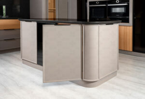 جزیره‌ی آشپزخانه با کابینت منحنی و درب باز، نمایانگر فضای داخلی و طبقه‌بندی چوبی