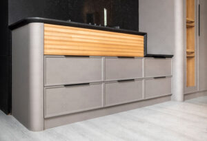 آشپزخانه با طراحی خمیده، پنل‌های چوبی عمودی و ترکیب رنگ متضاد