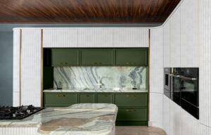 کابینت آشپزخانه با درب‌های منحنی سفید، گاز رومیزی روی جزیره و ترکیب رنگ سبز مات در قسمت بالایی