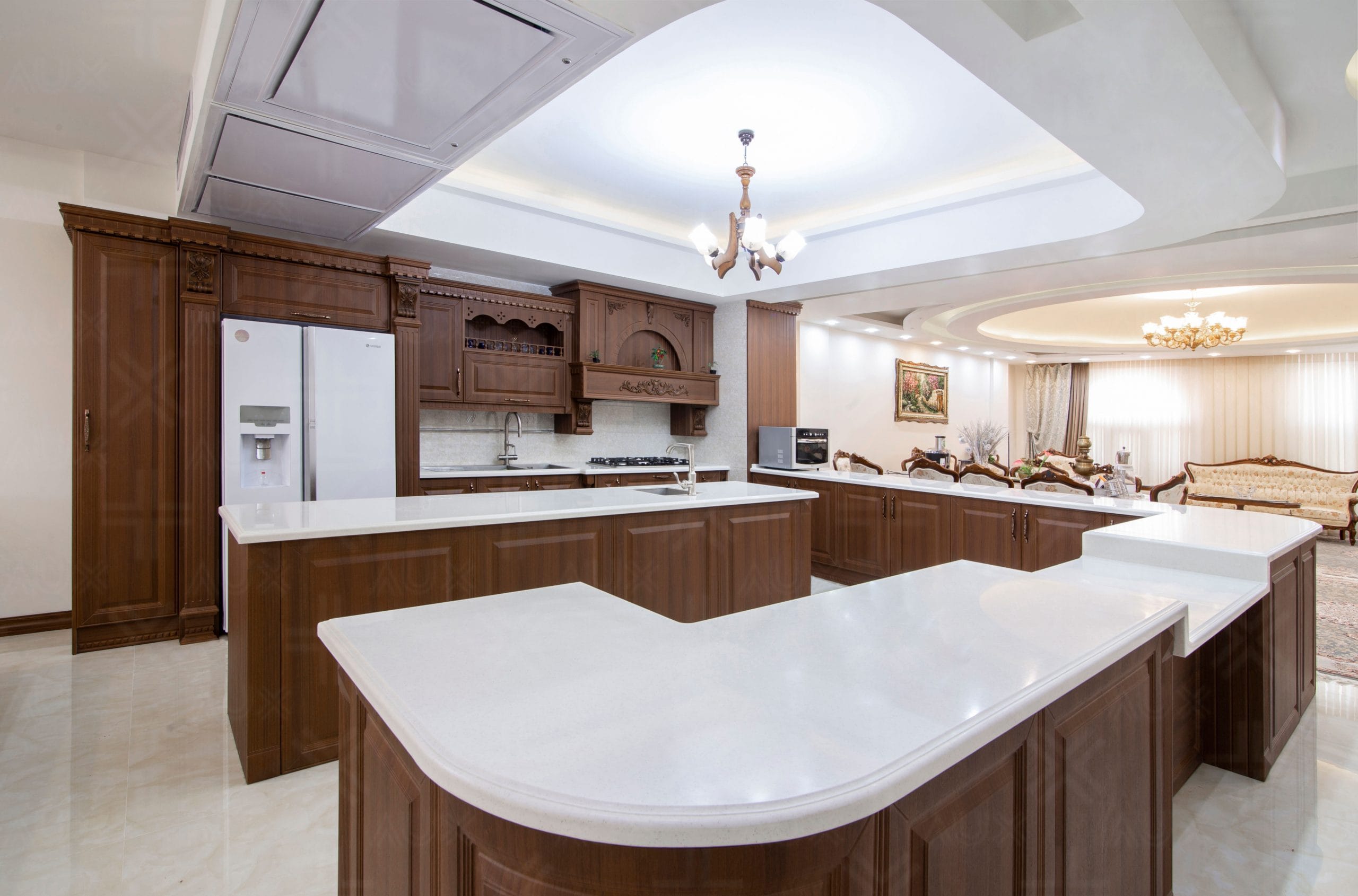 آشپزخانه با کابینت چوبی قهوه‌ای و صفحه رویه سفید در فضای باز