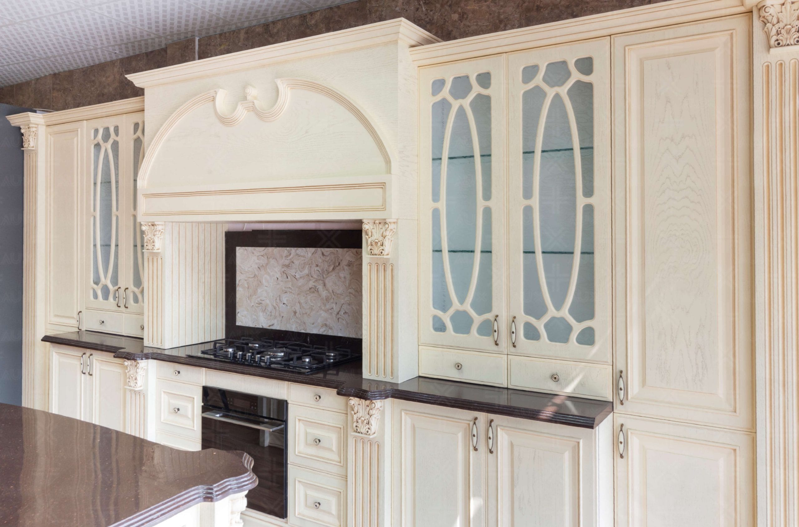 نمای کابینت چوبی کلاسیک آشپزخانه با درب‌ شیشه‌ای طرح‌دار و هود تزیینی