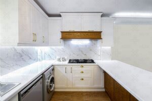 آشپزخانه مدرن با کابینت‌های سفید و جزیره چوبی با رویه سنگی