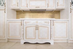 آشپزخانه با کابینت چوبی سفید کلاسیک و جزئیات طلایی برجسته