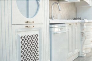 کابینت کلاسیک رنگ روشن با طراحی شبکه‌ای و سینک استیل در کنار آن