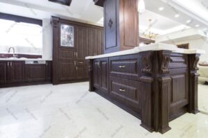 طراحی کلاسیک آشپزخانه با درب‌های چوبی و پنل شیشه‌ای نقش‌دار