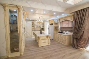 آشپزخانه کلاسیک با کابینت ممبران طرح چوب روشن، جزیره‌ی مرکزی و لوستر سقفی