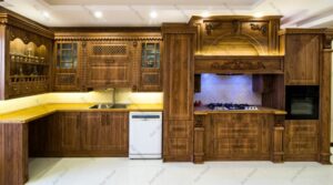 نمای روبرو از کابینت‌های کلاسیک ممبران با منبت‌کاری چوبی و هود تزئینی
