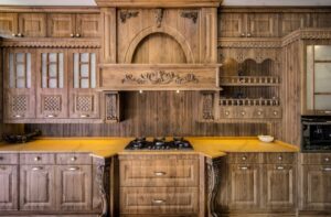 نمای روبرو از کابینت‌های کلاسیک ممبران با منبت‌کاری چوبی و هود تزئینی
