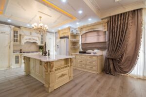 آشپزخانه کلاسیک با کابینت ممبران طرح چوب روشن، جزیره‌ی مرکزی و لوستر سقفی