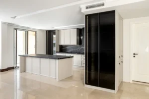 طراحی آشپزخانه نئو کلاسیک با استفاده از کابینت‌های سفید و مشکی و جزیره بزرگ، فضایی مدرن و کلاسیک را به نمایش می‌گذارد.