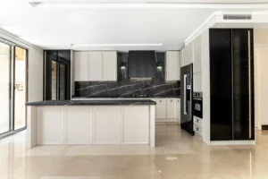 طراحی آشپزخانه نئو کلاسیک با استفاده از کابینت‌های سفید و مشکی و جزیره بزرگ، فضایی مدرن و کلاسیک را به نمایش می‌گذارد.