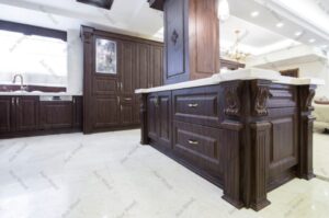 آشپزخانه لوکس با کابینت روکش چوب تیره و ویترین شیشه‌ای