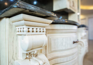 کابینت کلاسیک روکش چوب روشن با منبت‌کاری روی ستون‌ها و جزئیات ظریف.