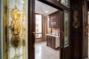 آشپزخانه کلاسیک با کابینت روکش چوب و شیشه‌های دکوراتی